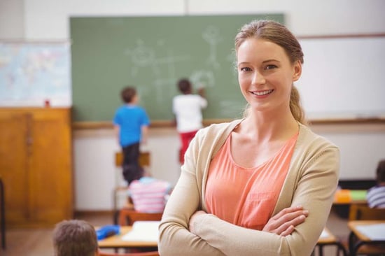 Pretty teacher smiling at camera at back of classroom at the elementary school-3