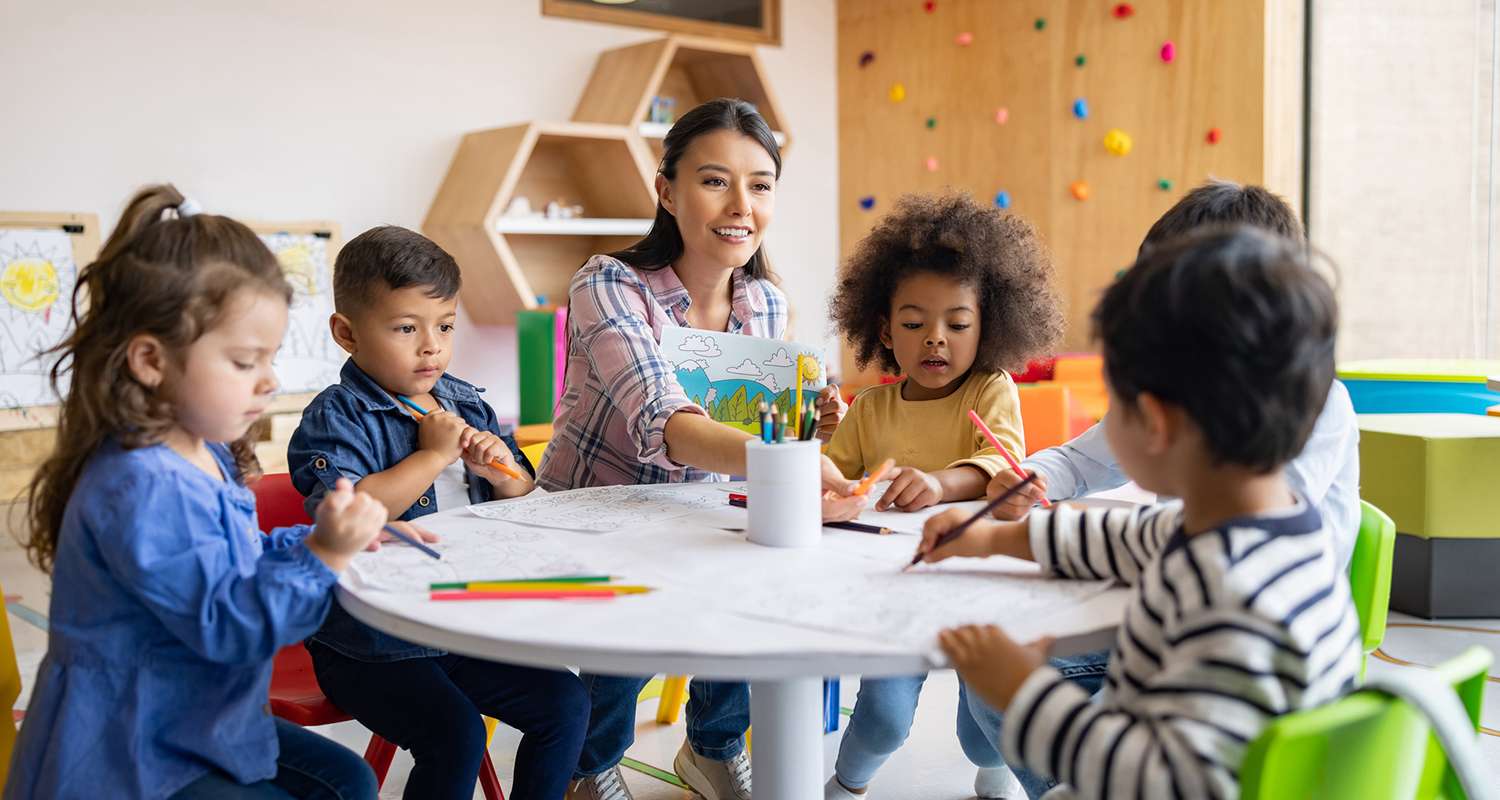 Teacher-at-a-table-with-preschoolers-who-are-drawing