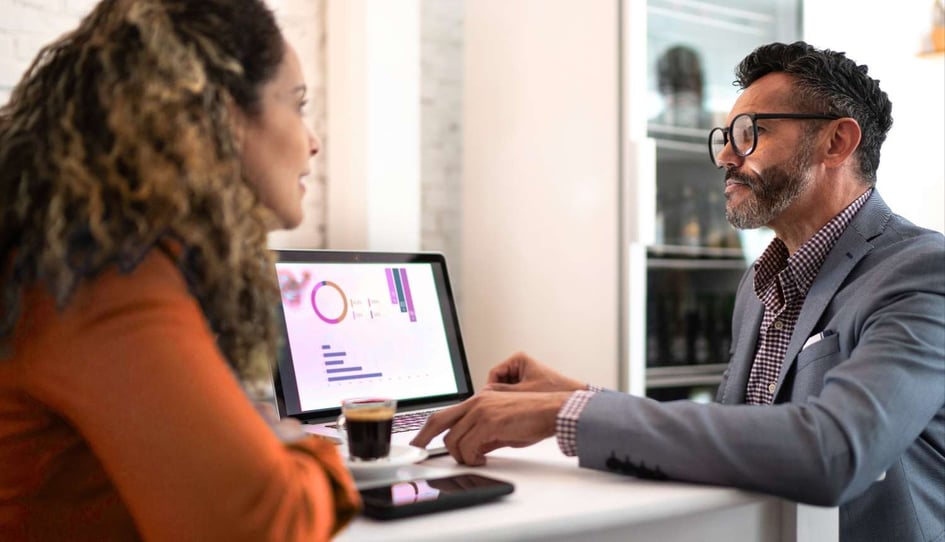 man and woman looking at statistics on computer