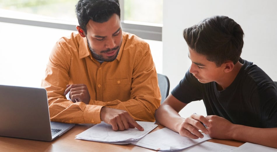 male tutor with high school student looking papers