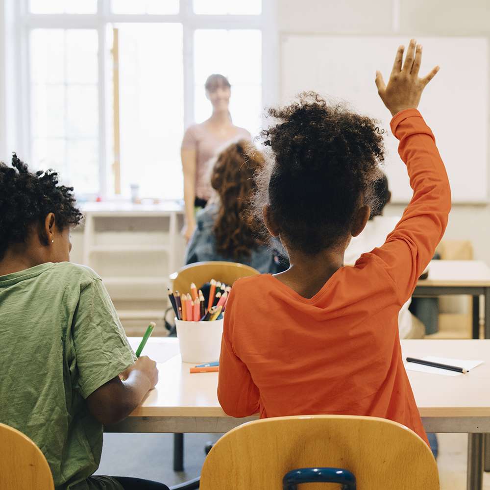 Young-elementary-school-girl-raising-her-hand-in-class