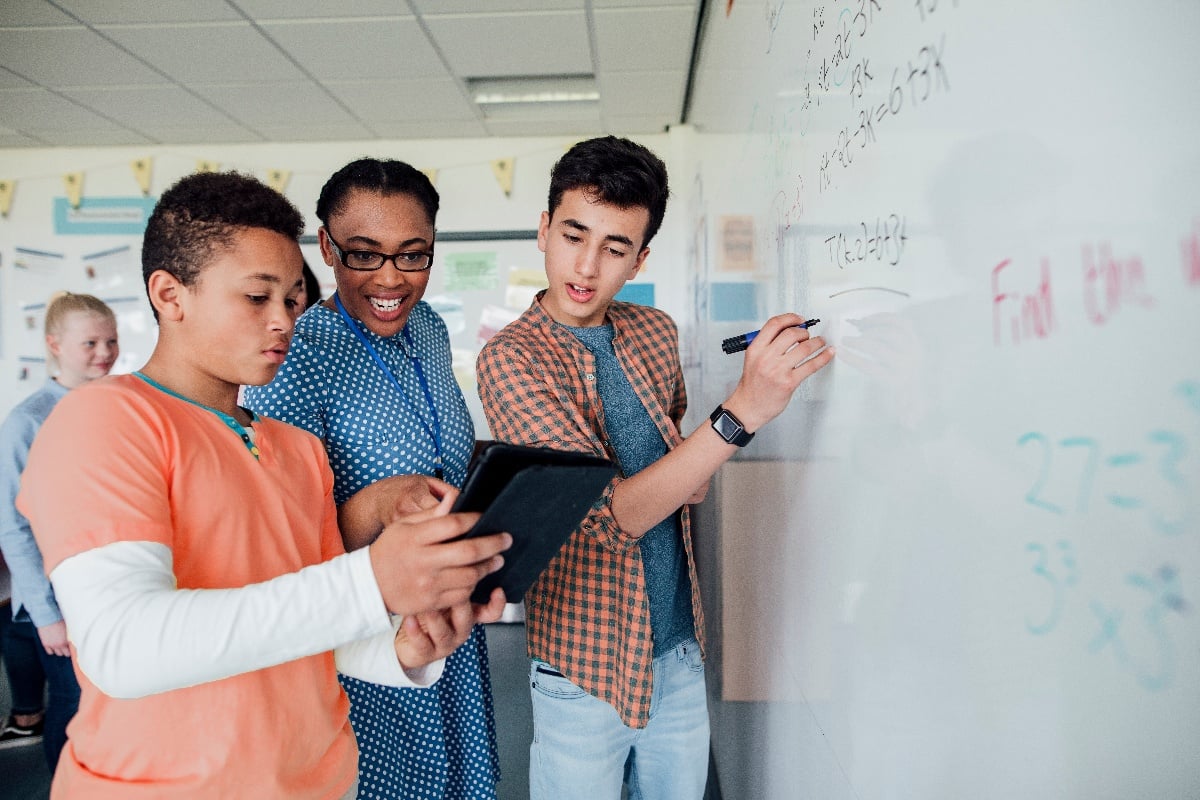 teacher at whiteboard with two students