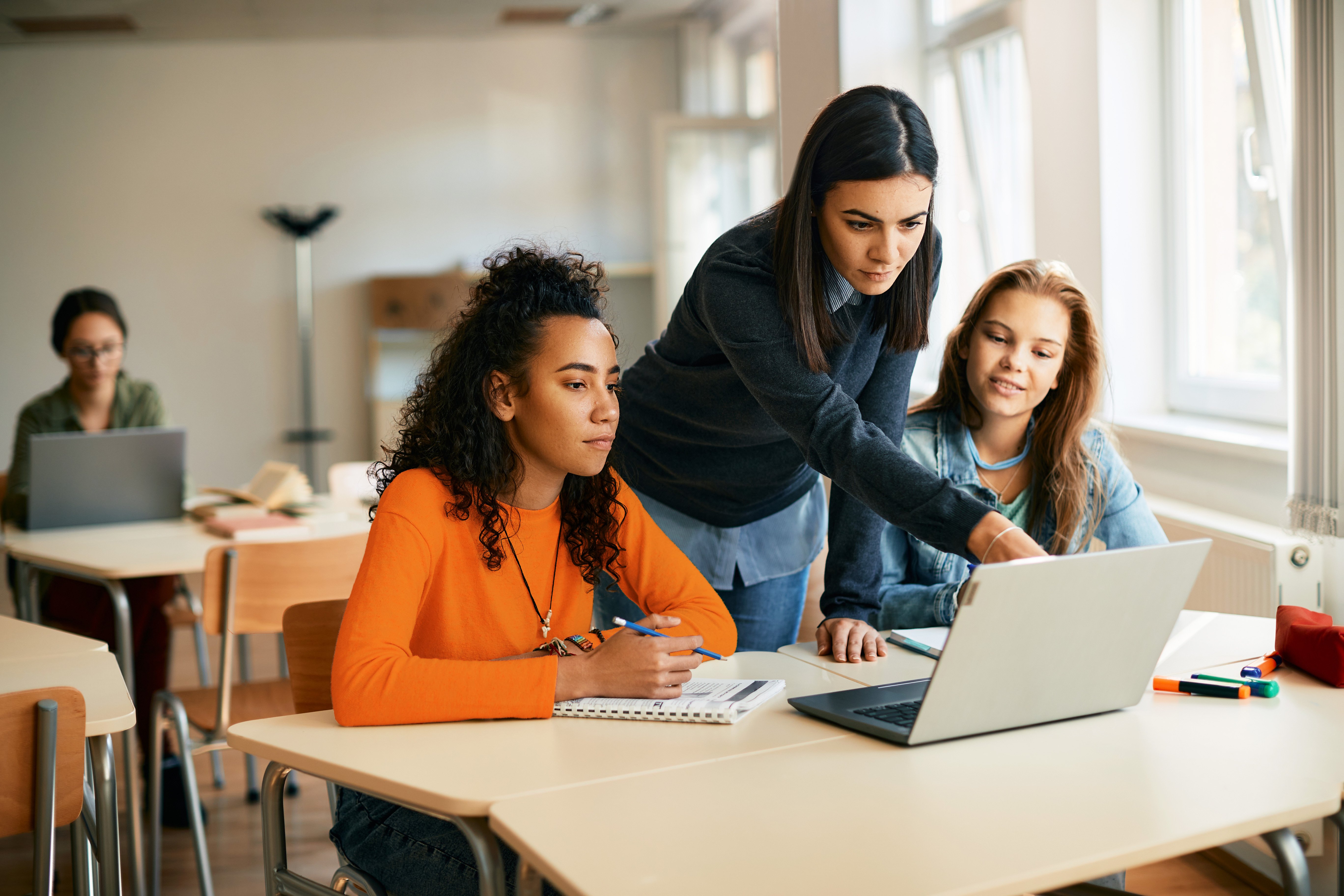 teacher with teens pointing at computer